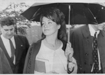 Alice Crimmins holding an umbrella surrounded by people