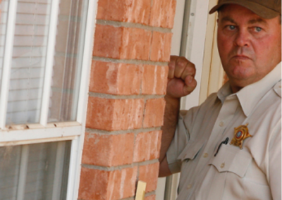 Wayne McCutchen, in uniform, knocking on a door