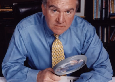 John Douglas holding a large magnifying glass