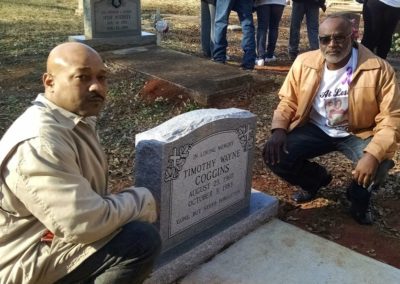 Timothy Coggin’s brothers, Ramon (left) and Tyrone (right) posing next to the long-awaited headstone for Timothy.