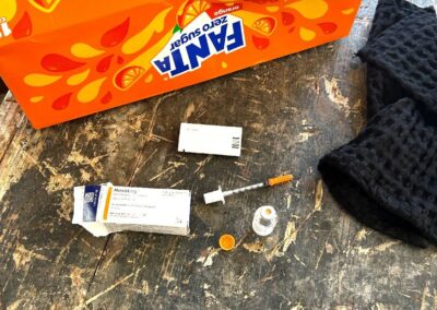 The Fanta box where a syringe, syringe cap, and partially used insulin vial are found.